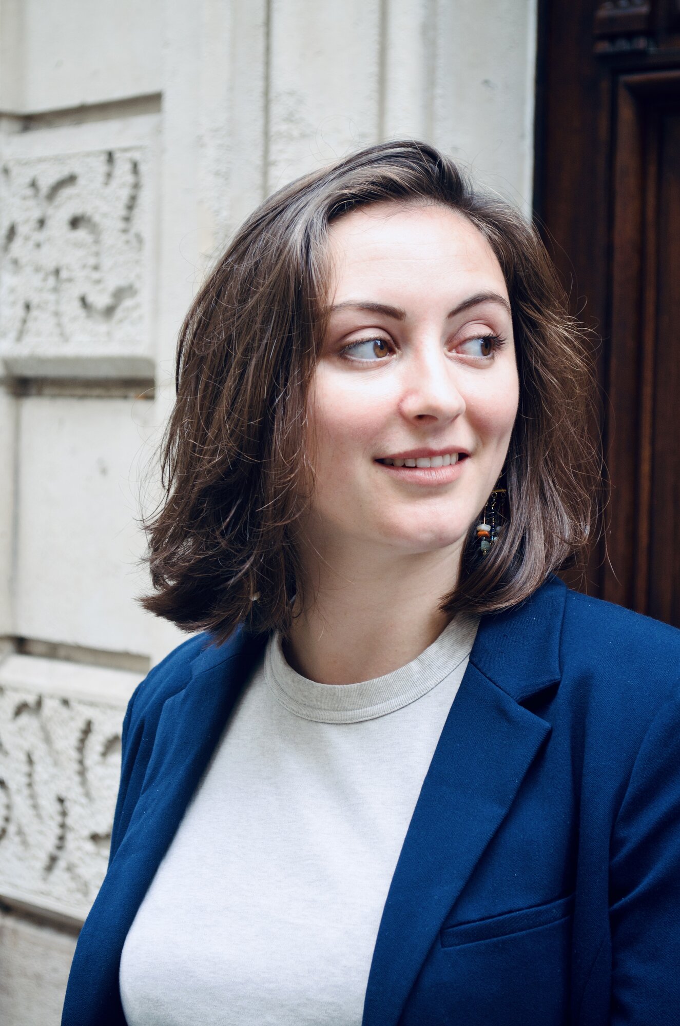 Julie Gamer, comédienne, portrait de trois-quarts en blazer bleu marine, regard hors champ
